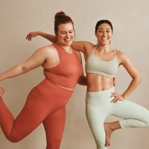 Zwei lachende Frauen in Sportkleidung in Yogaposen