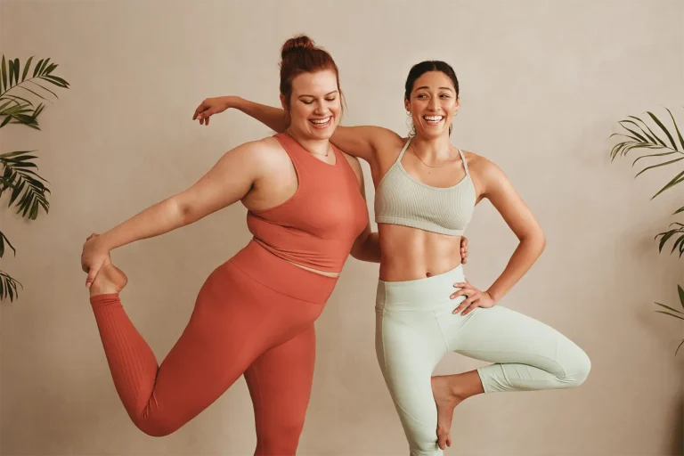 Zwei lachende Frauen in Sportkleidung in Yogaposen