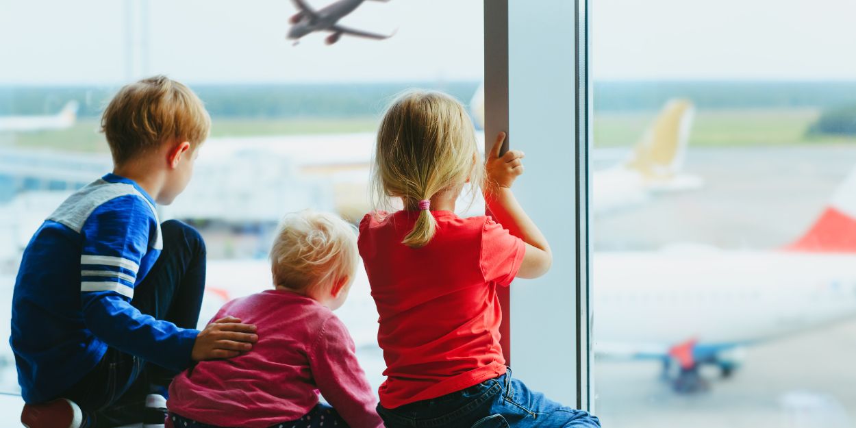 Drei Kinder schauen im Flughafen den Flugzeugen zu